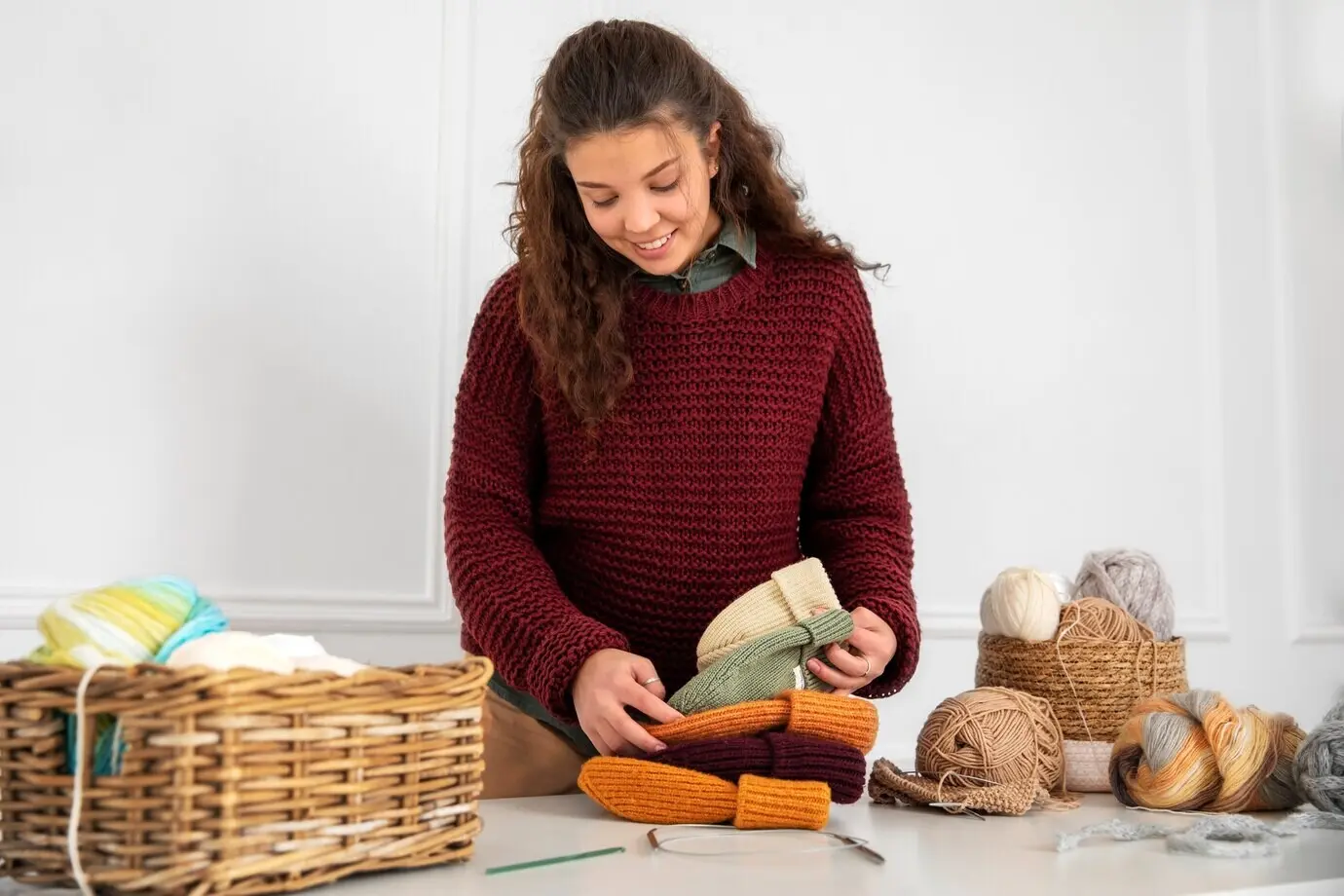 Halbnahe Aufnahme einer Frau, die gestrickte Mützen hält.