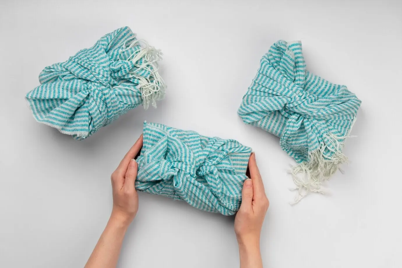 Draufsicht auf Hände, die ein Furoshiki-Paket halten.